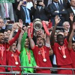 Liverpool’s English midfielder Jordan Henderson lifts the trophy as Liverpool players celebrate after winning the English FA Cup final football match between Chelsea and Liverpool, at Wembley stadium, in London, on May 14, 2022.